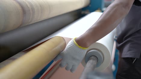 a close-up view of a worker’s hands in the textile lamination process, where they apply layers to enhance thermal insulation, water resistance, and durability in fabric