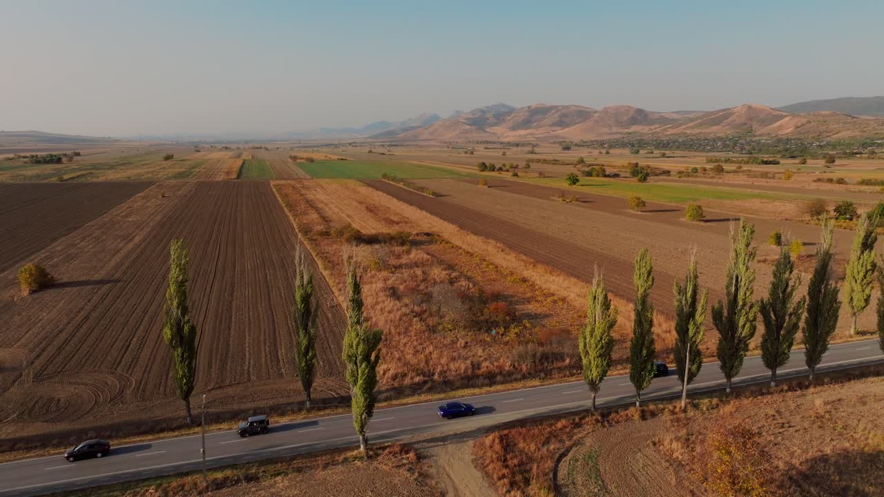 드론 추적 넓은  ⁇  파란 차량은  ⁇ 빛이 빛나는 포장 된 도로를 따라 산을 향해 운전,  ⁇ 빛 날 녹색 나무로 둘러싸여