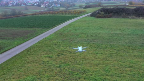 white quadcopter drone hovering over beautiful grass field on a sunny day