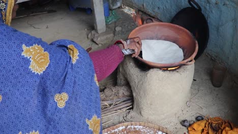 women-making-rice-bread-in-traditional-soil-vessels-at-wood-fire-from-different-angle-at-village