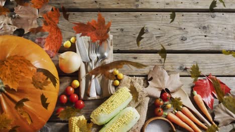 animation of halloween pumpkin, leaves and autumn produce on wooden background