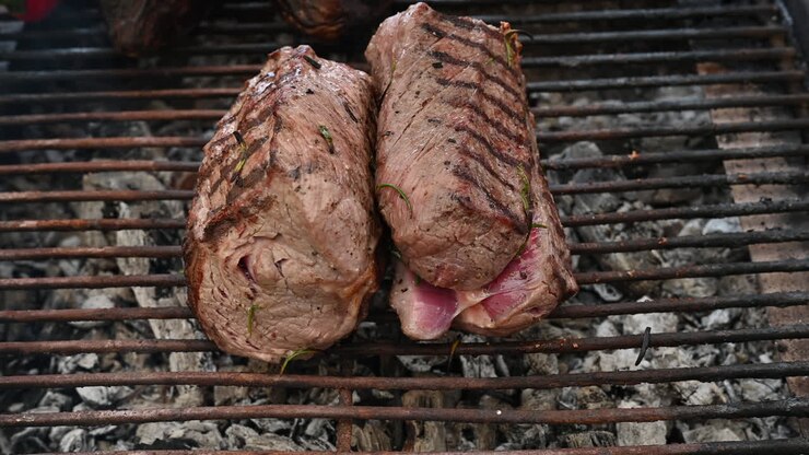 Potongan daging sapi sedang dipersiapkan di atas panggangan