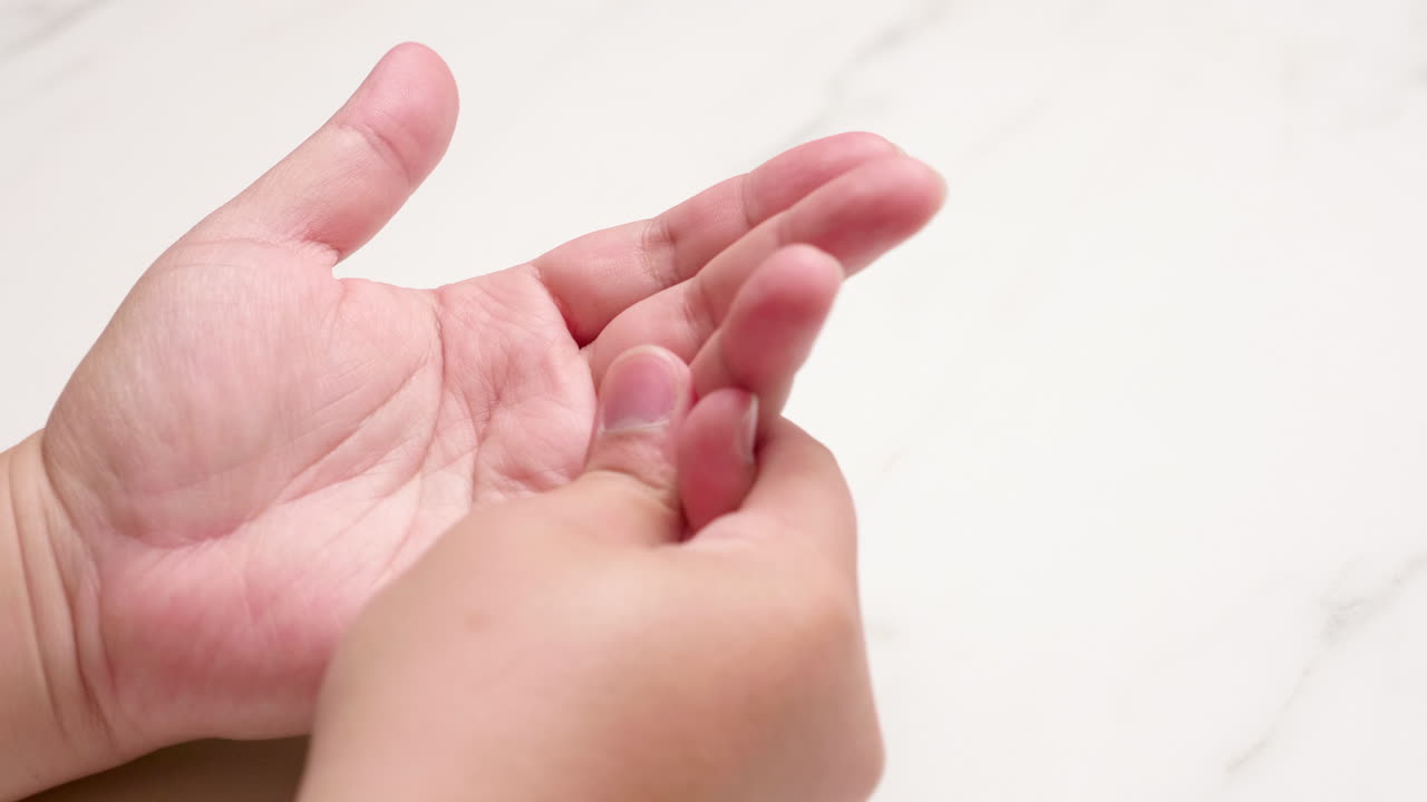 Squeezing and pinching an individual's left hand, then closing and opening it to relieve herself of pain and inflammation
