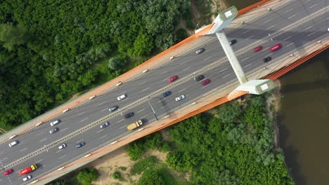 Stadtauto-Bewegt-Sich-An-Der-Autobahnbrücke-Auf-Hintergrund,-Glatter-Flussoberfläche,-Drohnenansicht