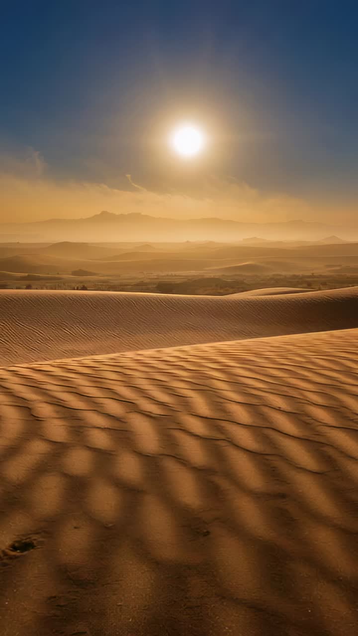 Video verticale: la camera avanza rivelando una duna increspata in un deserto soleggiato con sole e impronte