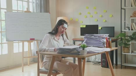 sick asian woman working hard with documents at the office