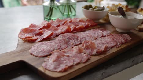 meaty appetiser on a wooden plank with extra sauces and olives