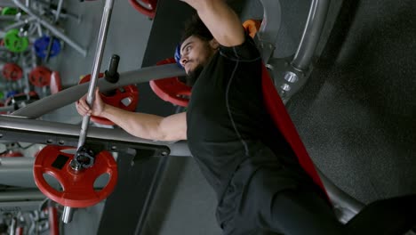 man with muscular physique spends hard workout lifting barbell in gym, slow motion