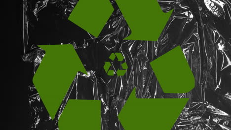 animation of green recycling icon over black plastic