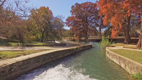 river flowing from bridge in park with white water showing as it drops to lower level and becomes a calm river