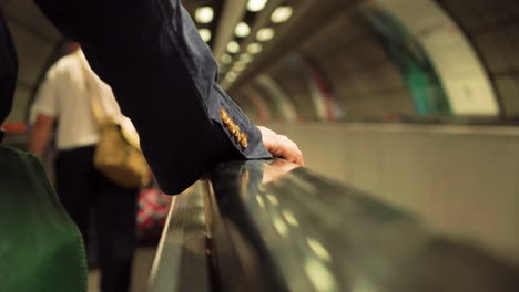 Viajando-En-Una-Escalera-Mecánica-Horizontal-En-El-Metro-De-Londres,-La-Manga-Del-Traje-Y-La-Mano-Visibles-Del-Jinete-Masculino