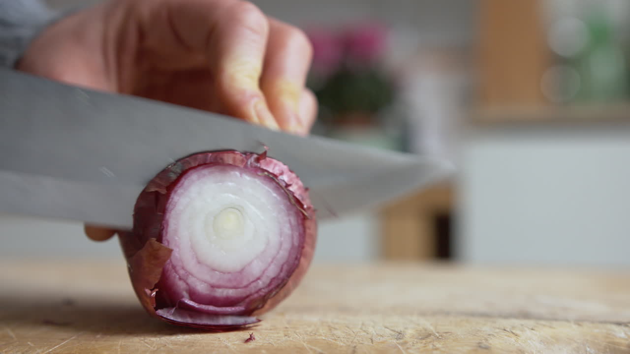 Close up woman's hand start slicing Italian red onions with a sharp knife in the kitchen