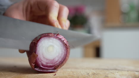 cerrar la mano de la mujer empezar a cortar cebollas rojas italianas con un cuchillo afilado en la cocina