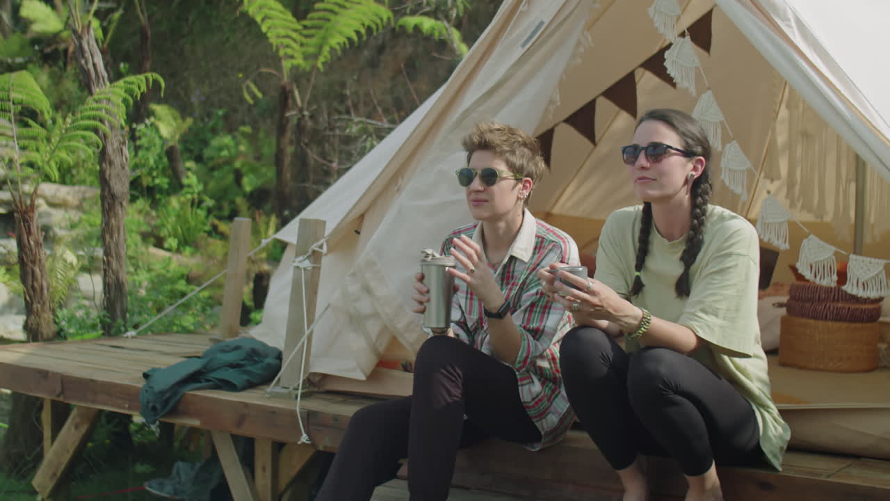 Two Female Tourists Talking over Tea at Glamping