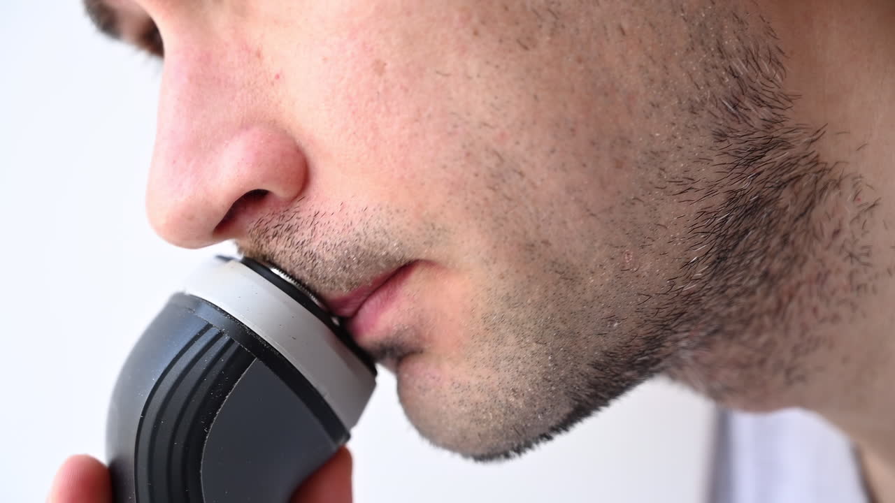 Close up of man using electric shaver on chin and face