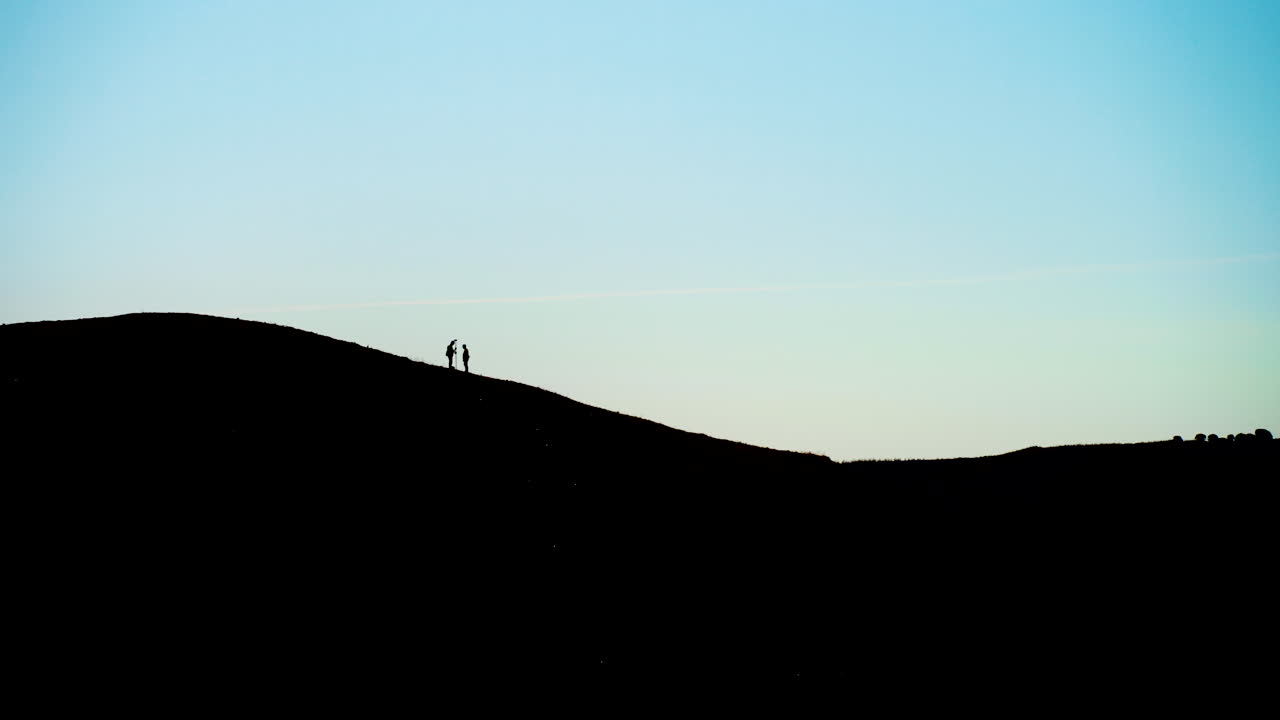 plano general de la silueta de los hombres que realizan estudios topográficos en la cima de la colina