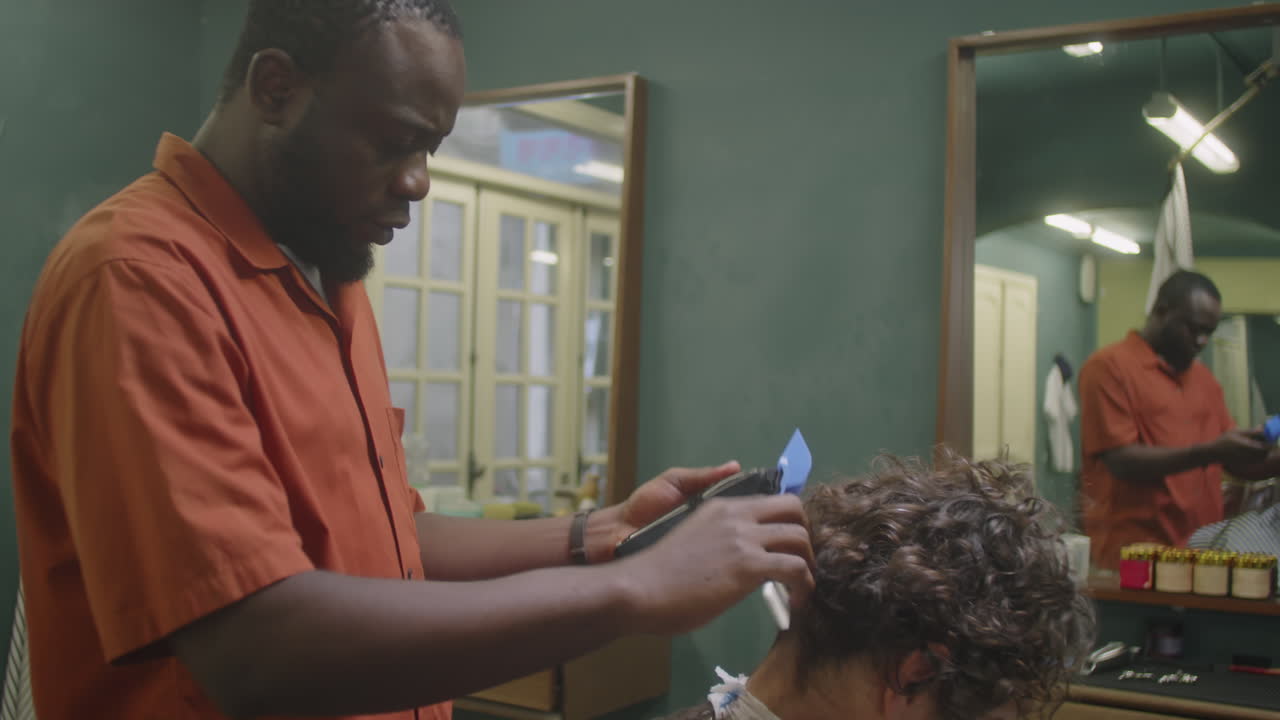 Sort barber giver kunde klipning med trimmere og kam