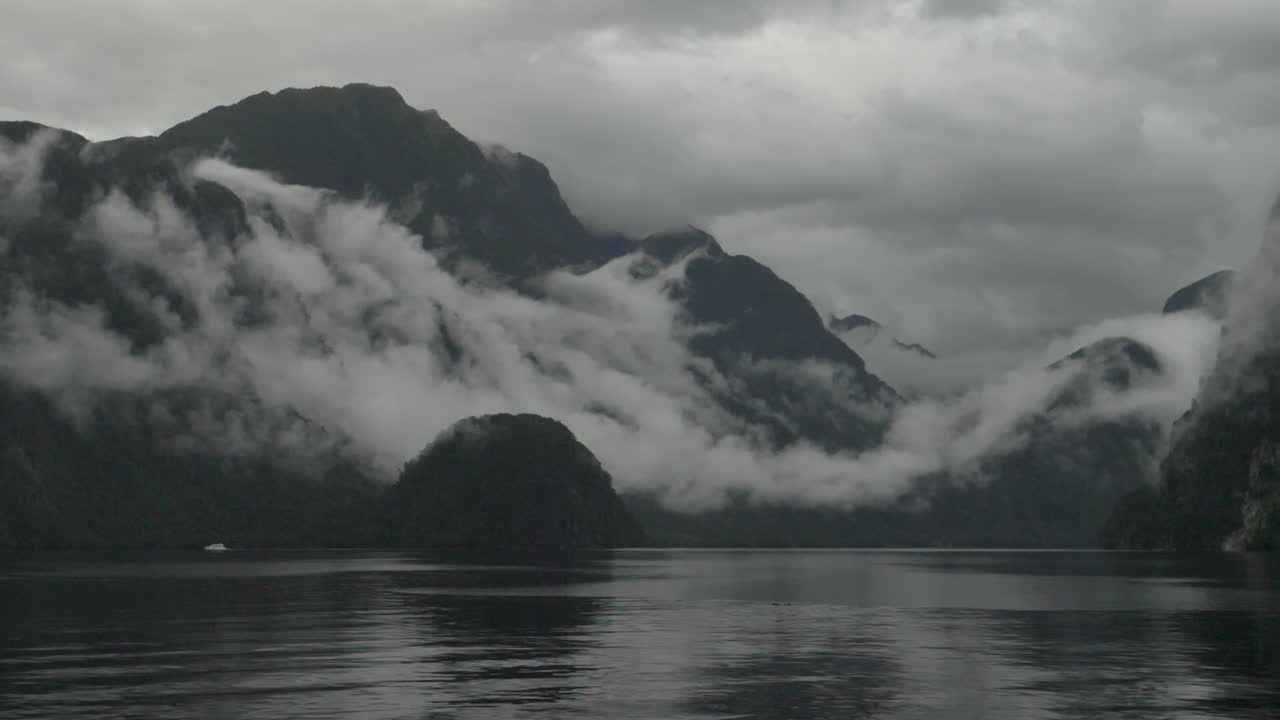 앞면 에 물 이 있는 의심 스러운 소리 로 안개 와 구름 이 가득 찬 산 들 을 가로질러 느린 움직임 으로  - 파테아, 뉴질랜드