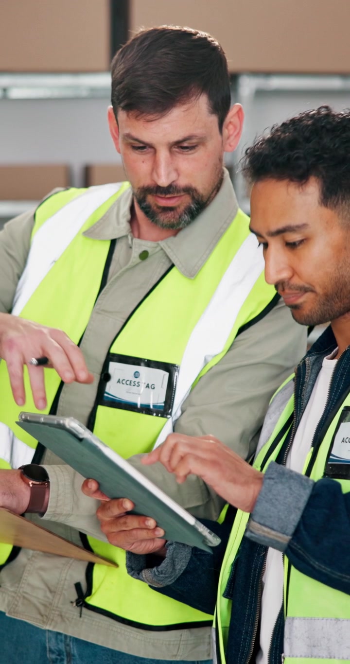 Lavoratori di magazzino che discutono di logistica usando un tablet digitale