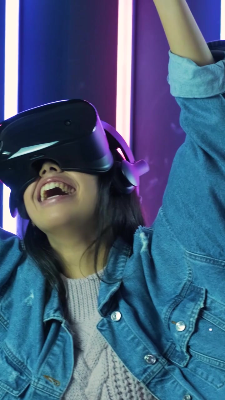Giovane donna entusiasta che sperimenta la realtà virtuale in uno studio al neon