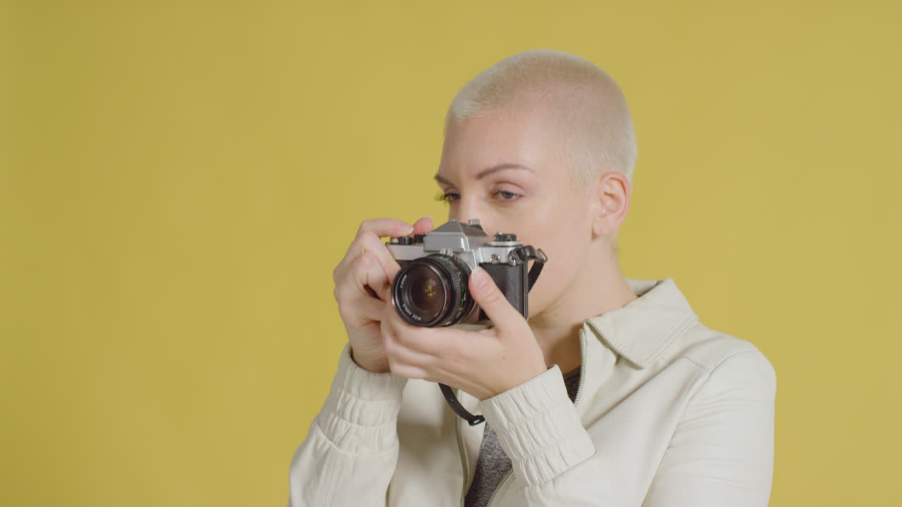 노란색 배경 02에 대해 빈티지 slr로 포즈를 취하는 여성 백인 모델