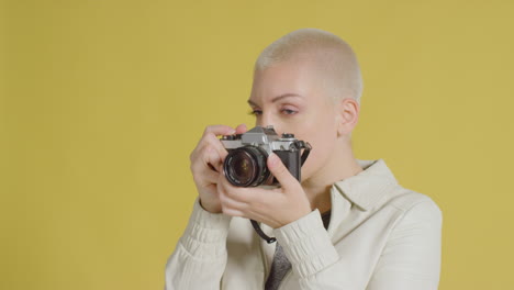 кавказская модель позирует с винтажной фотокамерой на желтом фоне 02