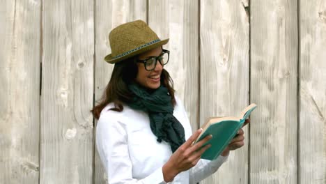 Hipster-reading-against-wooden-fence