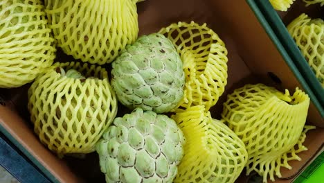 woman of african ethnicity choosing a custard apple from a market stall