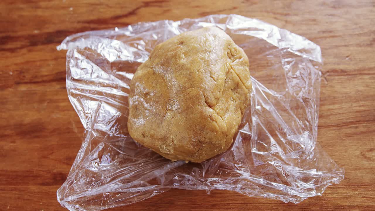 la masa colocada sobre una envoltura de plástico en una mesa de madera 4k