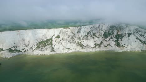 Distant-view-Beachy-Head-Lighthouse,-white-cliffs,-foggy-sky-and-sea-taken-by-dji-mini-3-pro-drone-in-Eastbourne-England