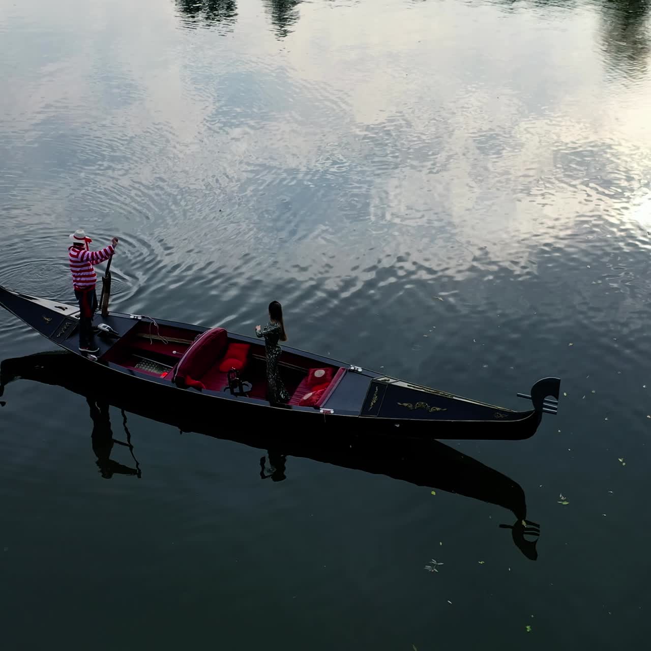 Luxury woman travels in gondola. Italian gondola floating on the blue river background. Woman standing in a boat. Top view.