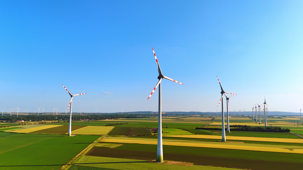 Wind turbines produce clean energy. Wind turbines stand tall under a clear blue sky, producing clean energy in expansive green fields during daylight