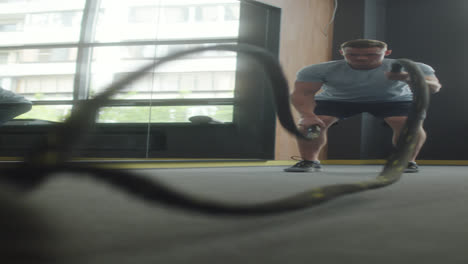 man doing battle ropes in gym