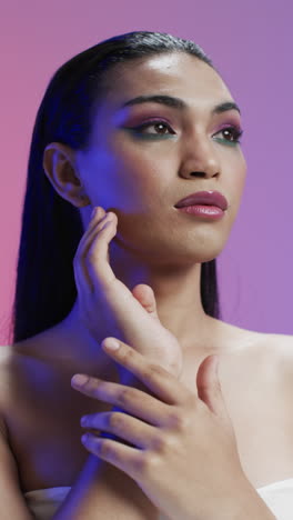 vertical video of biracial woman with black hair and make up touching face, copy space, slow motion