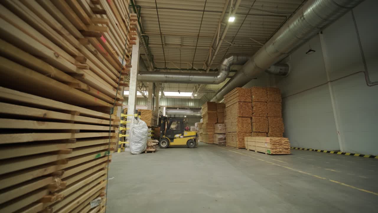 Grande magazzino industriale con cataste di legname e carrello elevatore