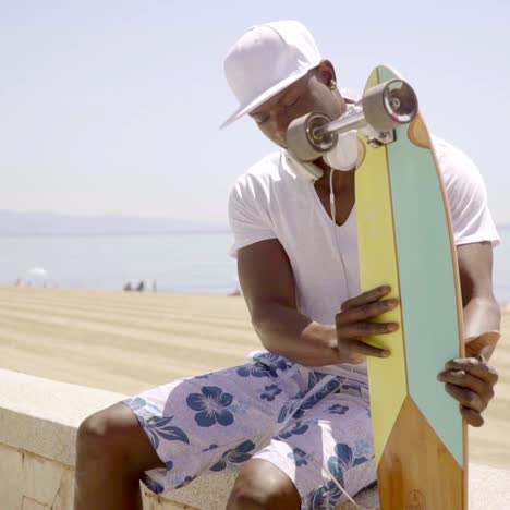 handsome young black man seated on beach wall