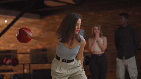 retrato de una joven mujer morena hace el lanzamiento final con una pelota de bolos y gana el juego con el apoyo y la alegría de sus amigos de diferentes nacionalidades. regocijarse y celebrar la victoria