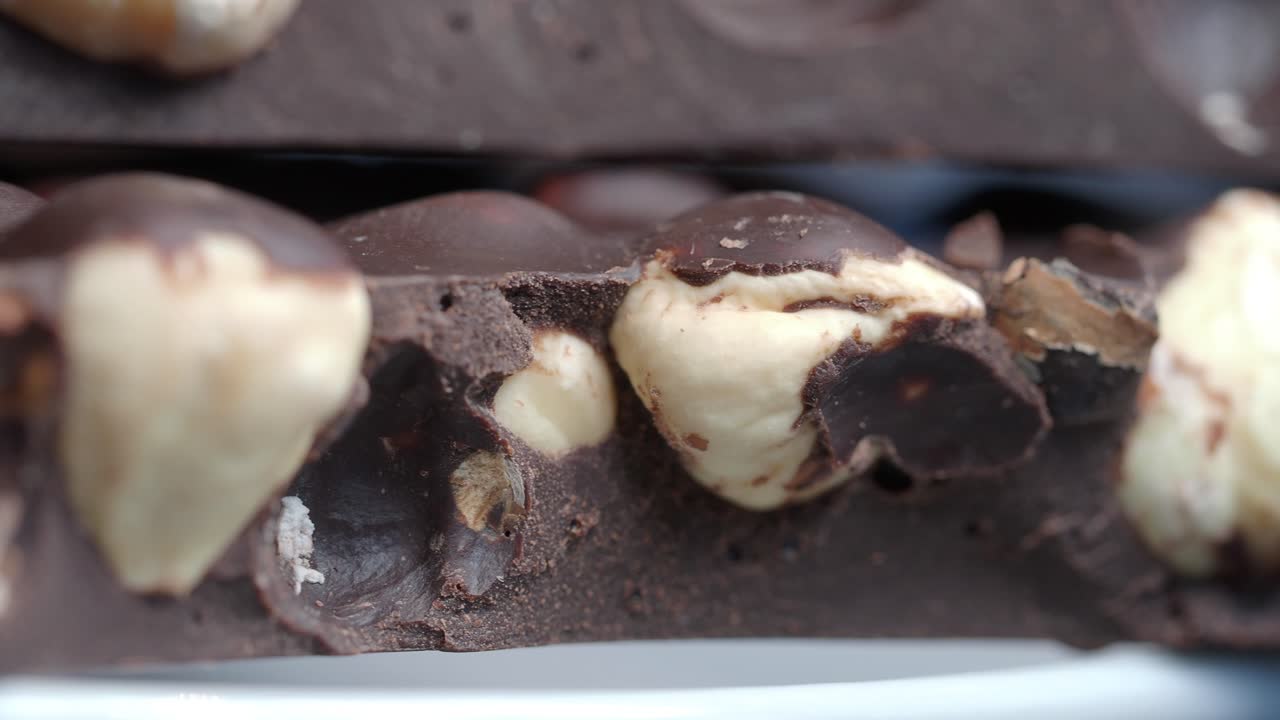 Primo piano di una barretta di cioccolato fondente con nocciole intere