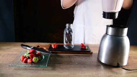 a woman pouring strawberries smoothie from jug into glass