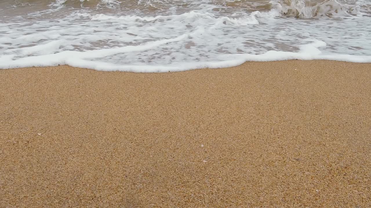 Statische Aufnahme aus niedriger Perspektive einer Strandwelle, die auf die Kamera zukommt