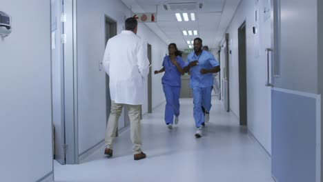 grupo diversificado de médicos masculinos e femininos correndo urgentemente pelo corredor do hospital