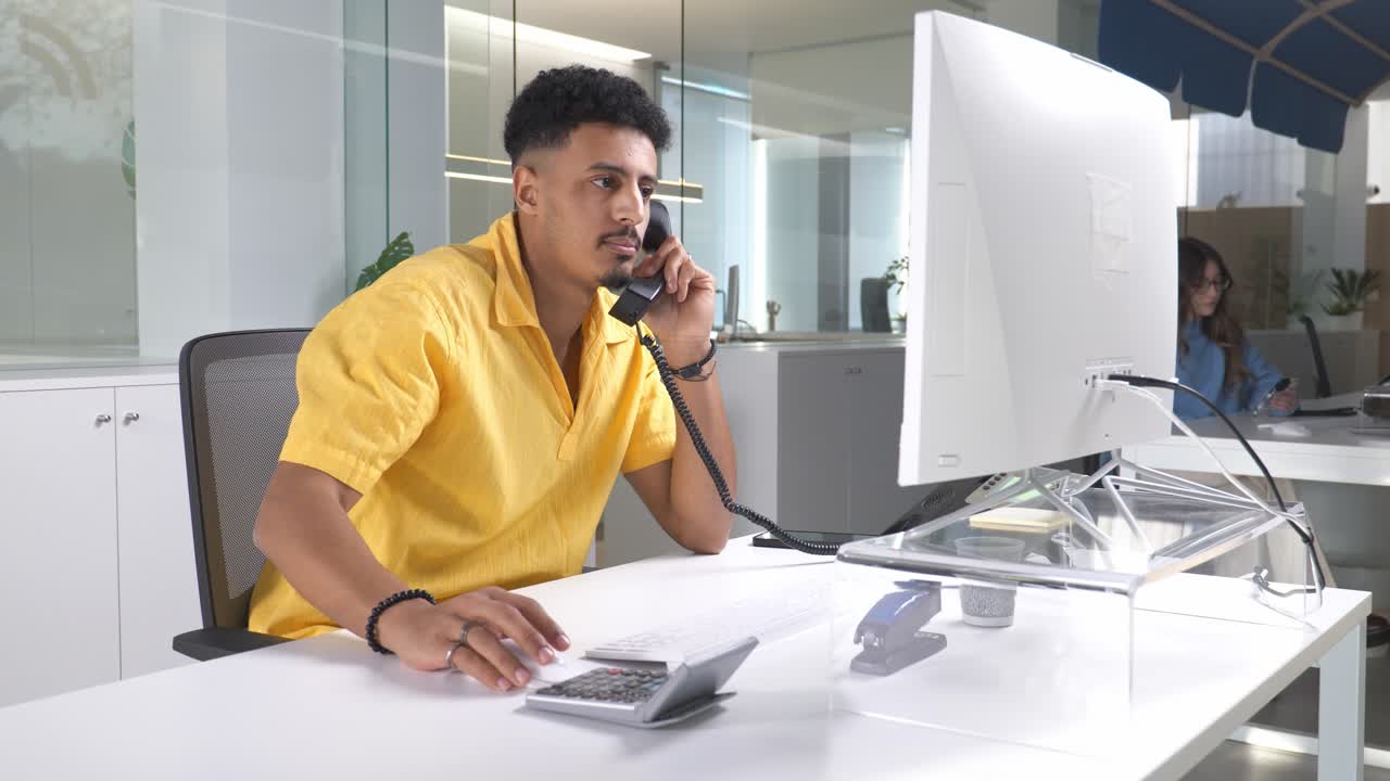 Empleado de oficina haciendo una llamada telefónica y usando una calculadora