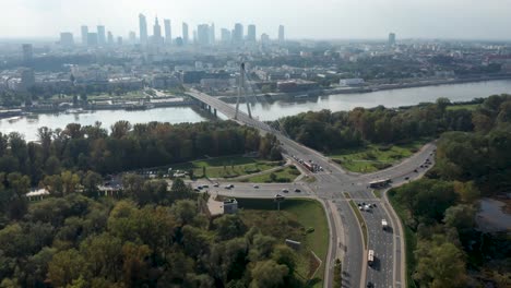 Aerial-drone-view-of-Warsaw-skyline,-Vistula-river,-Świętokrzyski-Bridge-and-road-junction-in-the-foreground