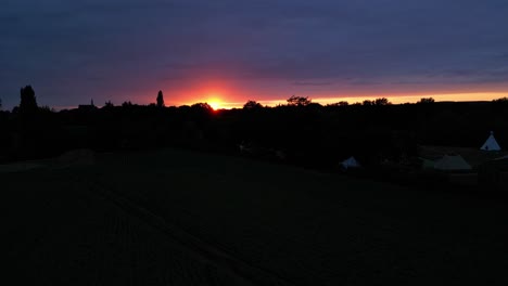 toma aérea de paralaje del cielo dorado de la puesta de sol naranja con vista al paisaje de silueta