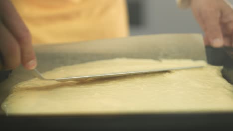 chef spreading a biscuit dough on a baking sheet