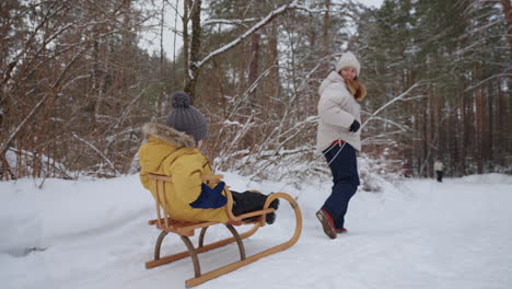 mother and little son are spending time and having fun in winter forest in weekend happy family