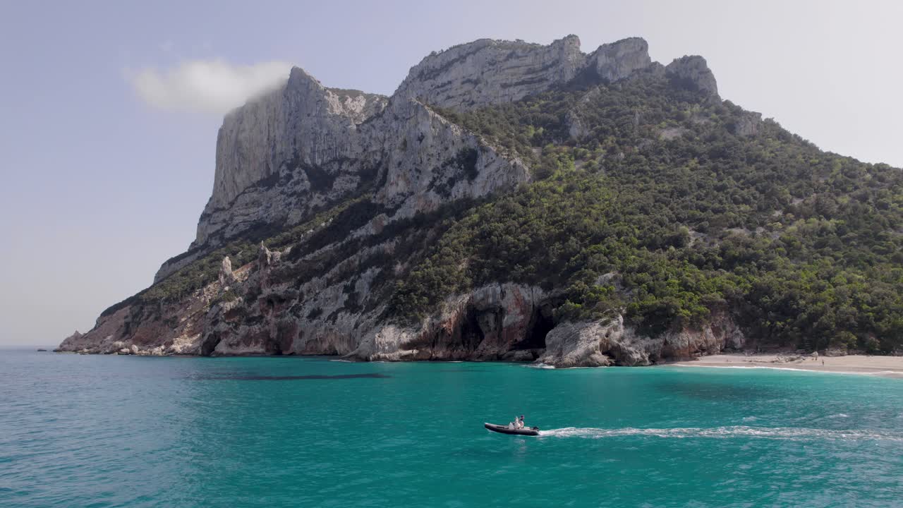 Motoscafo su mare turchese con scogliere maestose e spiaggia