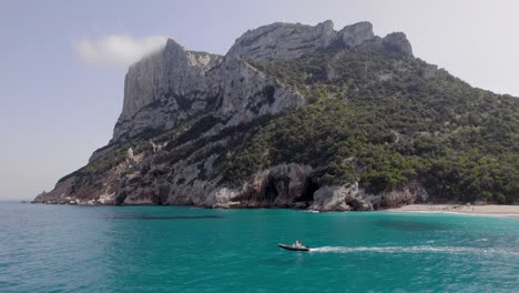 Motorboat on Turquoise Sea with Majestic Cliffs and Beach