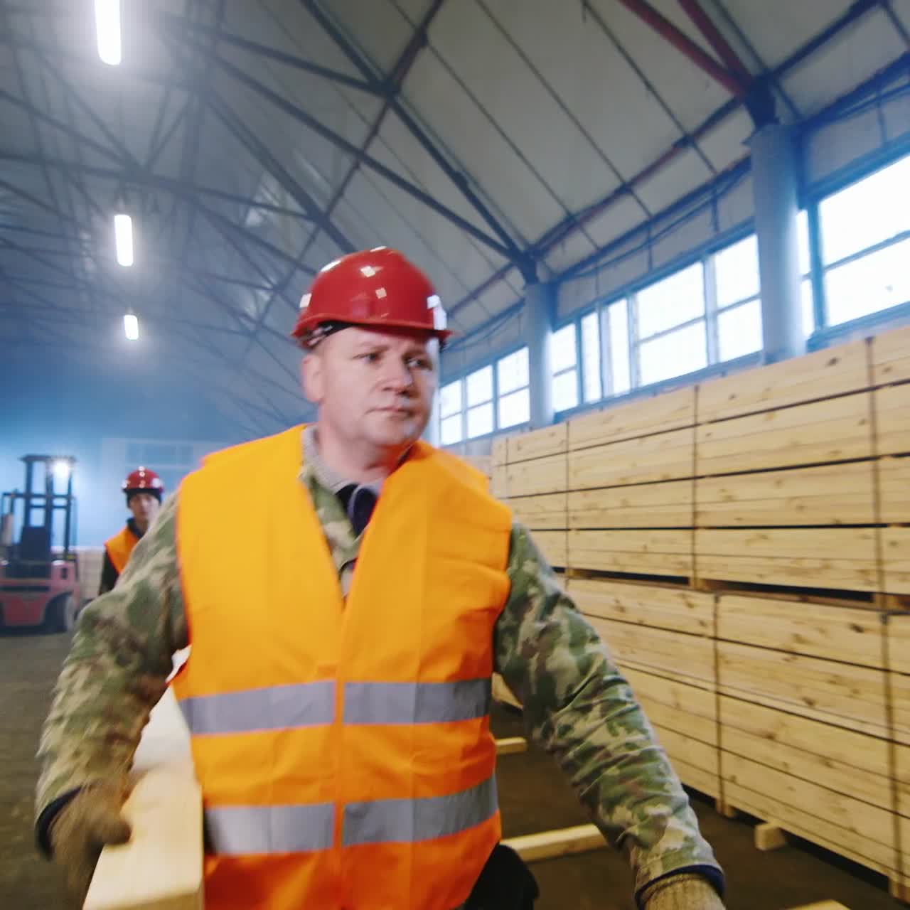 Un gruppo di operai sposta assi di legno.