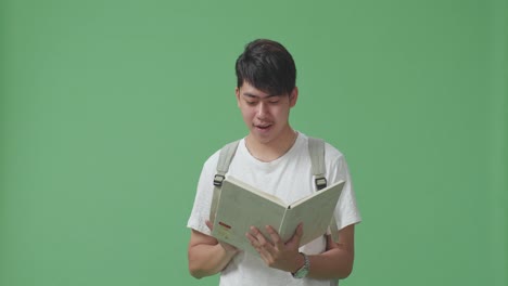 행복한 아시아 남자 학생이 그린 스크린 스튜디오에서 책을 읽습니다.
